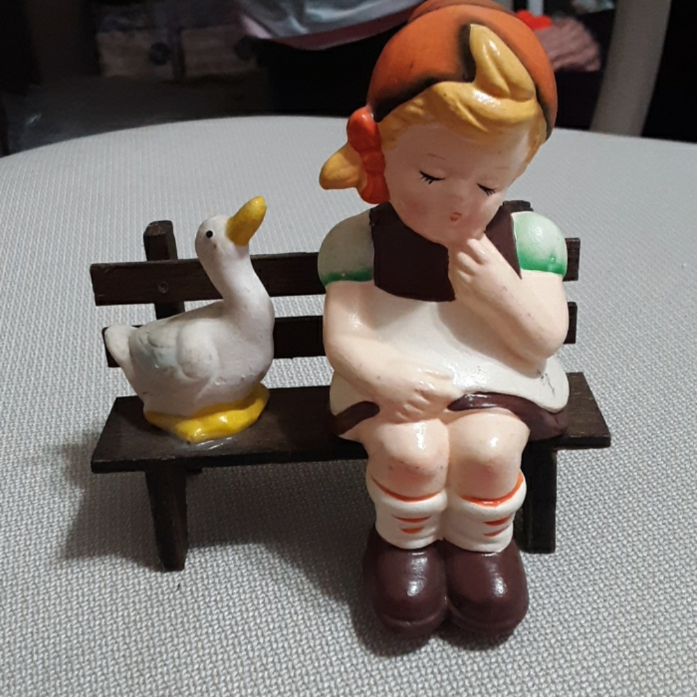 Ceremic child with duck on bench